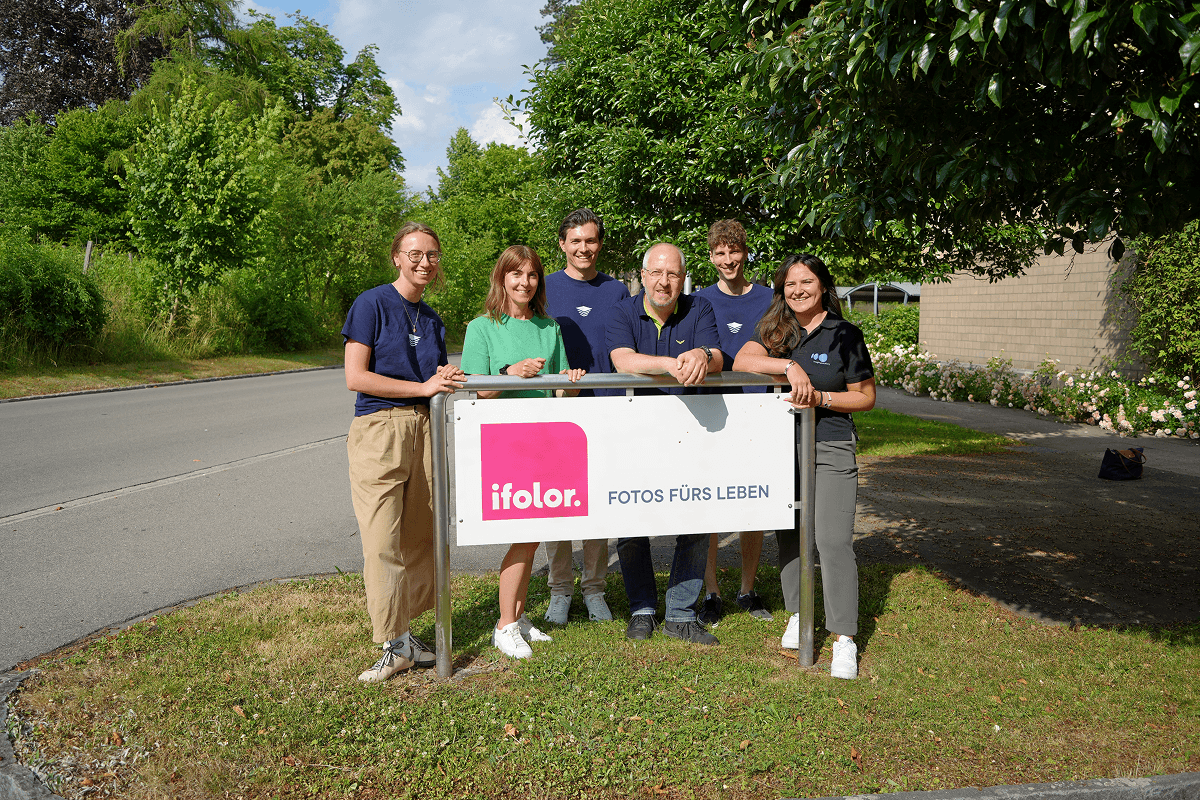 Group photo of Viesus and ifolor team members holding ifolor sign outside the Kreuzlingen headquarters