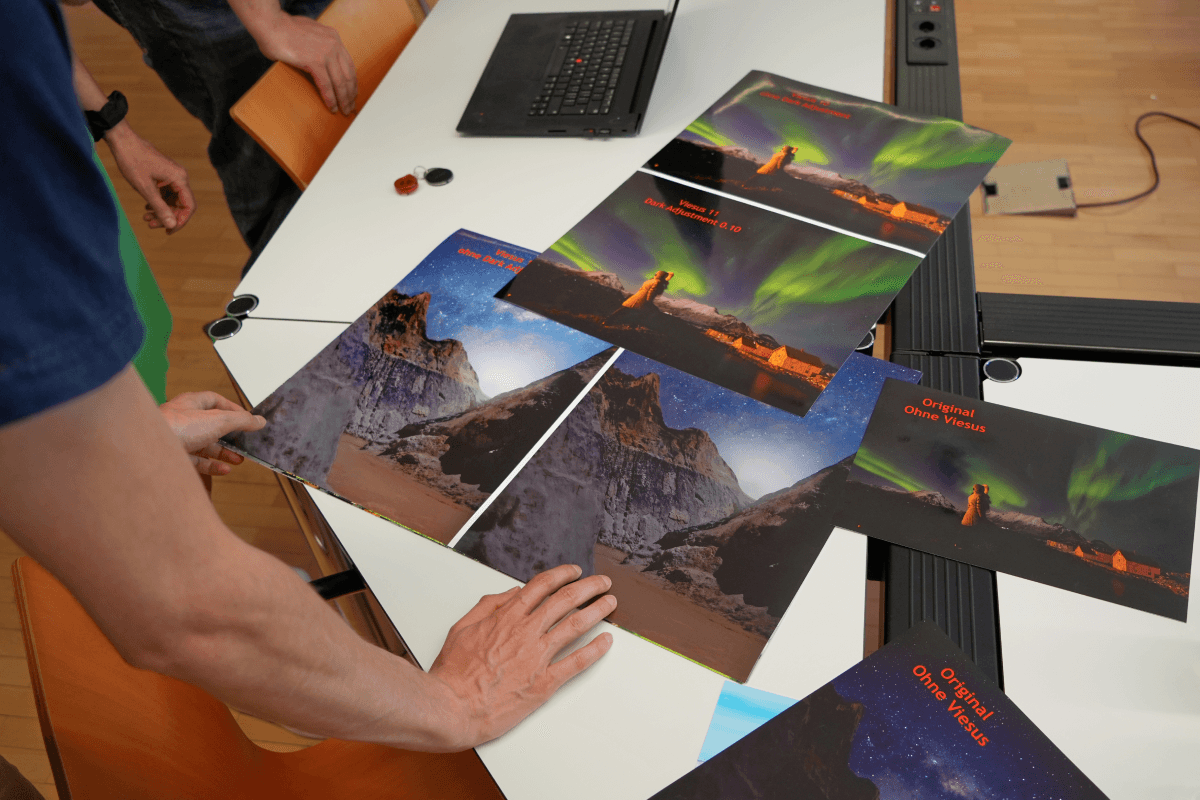 Hands inspecting large printed photo samples on a table at ifolor, illustrating quality variations from low-resolution uploads